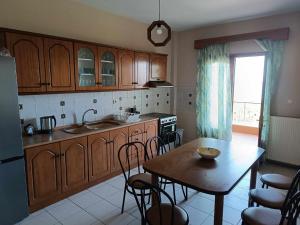 a kitchen with wooden cabinets and a table and a dining room at Rainbow Castle Villa neos panteleimonas in Neos Panteleimonas