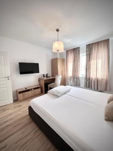 a bedroom with a large white bed and a television at Armonia Apartments in Timişoara