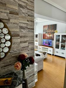a living room with a stone wall and a tv at Suances primera línea de playa in Suances