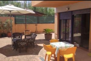eine Terrasse mit Tischen und Stühlen und einem Sonnenschirm in der Unterkunft Piso planta baja y gran patio con piscina comunitaria de alquiler temporal in Daimús