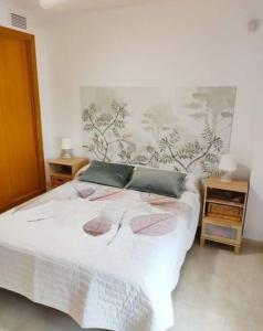 ein Schlafzimmer mit einem weißen Bett und zwei Kissen in der Unterkunft Piso planta baja y gran patio con piscina comunitaria de alquiler temporal in Daimús