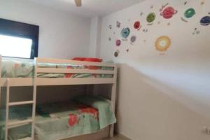 ein Schlafzimmer mit zwei Etagenbetten und einer Wand mit Aufklebern in der Unterkunft Piso planta baja y gran patio con piscina comunitaria de alquiler temporal in Daimús + 3 Fotos