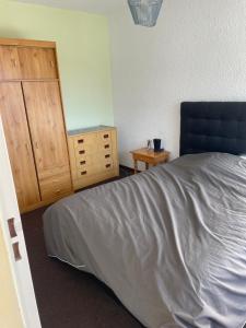 Un dormitorio con una cama y un armario de madera. en T2 Praloup 1500, en Uvernet