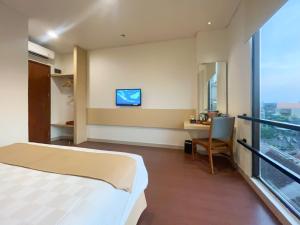 a hotel room with a bed and a desk and a television at Hotel 88 Embong Malang Surabaya By WH in Surabaya