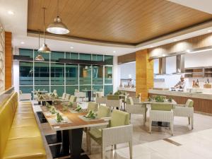 a restaurant with a long table and chairs at Hotel Santika Cikarang in Cikarang