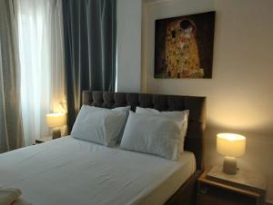 a bedroom with a bed with white sheets and two lamps at Kallithea Central Apartment in Kallithea Halkidikis