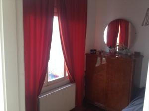 a room with a window with red curtains and a mirror at Kınalıada manzaralı ev in Adalar
