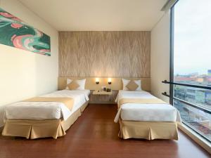 Dos camas en una habitación con una gran ventana. en Hotel 88 Embong Malang Tunjungan Surabaya by WH - Breakfast with The Best View on The Highest Floor and Strategic Location in The City Center, en Surabaya