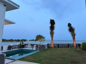 a house with a swimming pool and two palm trees at Cape House in Ban Bang Kaeo