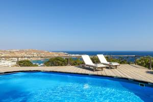 a swimming pool with two lounge chairs and the ocean at Amazing Sea View, Mykonos Cycladic Villa, Priv Pool in Mýkonos City