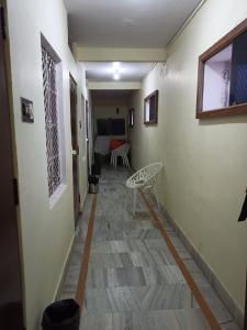 a hallway with a chair and a room with a bed at Hotel Alka in Varanasi