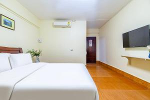 a bedroom with a white bed and a flat screen tv at 万象莉莉酒店 Lilyhotel in Vientiane