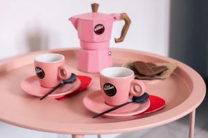 ムラヴェーラにあるAppartamento Le Margheriteのピンクのテーブルの上には、ピンクのカップが2つとブレンダーが置いてある