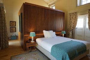 a bedroom with a large bed with a wooden headboard at Hotel Paço de Vitorino in Ponte de Lima