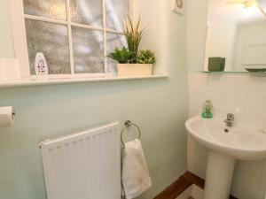 a white bathroom with a sink and a window at Lyndale Cottage in Bradwell +13 photos