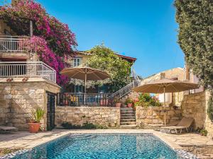 a swimming pool with two umbrellas and a house at Cyprus Villages Hotel & Restaurant - Central Location - Bed & Breakfast - With Access To Pool And Stunning Views in Tochni