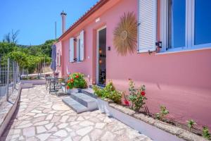 a pink house with a table and chairs outside at Villa Spirida at Drakopoulata in Agia Effimia +18 photos