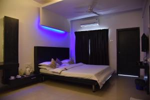 ein Schlafzimmer mit einem Bett mit violettem Licht in der Unterkunft Hotel Rama Heritage in Nashik + 106 Fotos