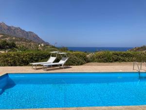 a blue swimming pool with two white chairs and the ocean at Abba Sixty - View, Pool & Parking - 200mt Sea in Tertenìa