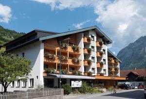 a building with flowers on the balconies on a street at Hotel Kanisfluh in Mellau