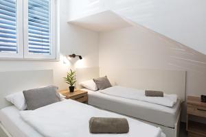 two beds in a room with white walls and windows at Villa THALIA in Tisno
