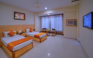 a hotel room with two beds and a television at Wingston A TreeHouse Hotel, Goverdhan in Govardhan