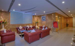 a lobby with red leather couches and a television at Wingston A TreeHouse Hotel, Goverdhan in Govardhan