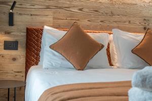 a bed with white pillows and a wooden wall at Home Seventyfive in Ponte di Legno