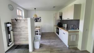 a kitchen with white cabinets and a sink and a toilet at Ferienwohnung Emma s Fehnhaus, 55183 in Stickhausen