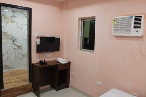 a room with a television and a desk with a phone at Park Royale Hotel in Kolkata