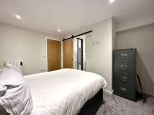 a bedroom with a large white bed and a dresser at Modern Ground Floor Apartment in Midsomer Norton