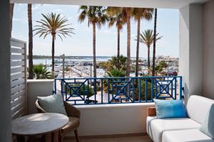 a balcony with palm trees and a view of the ocean at Hotel Honucai in Colònia de Sant Jordi
