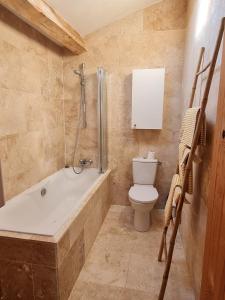 a bathroom with a tub and a toilet and a sink at Les volets bleus in Brie-sous-Mortagne