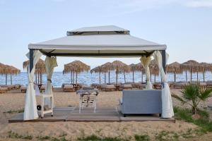 a gazebo on the beach with chairs and tables at Princess Resort, Santikos Collection in Agia Paraskevi