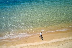 un homme se promenant sur la plage près de l'océan dans l'établissement Princess Resort, Santikos Collection, à Agia Paraskevi