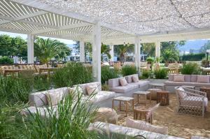 a patio with white couches and tables and chairs at Princess Resort, Santikos Collection in Agia Paraskevi