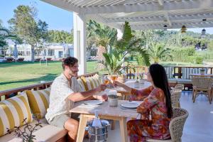 a man and woman sitting at a table with wine glasses at Princess Resort, Santikos Collection in Agia Paraskevi