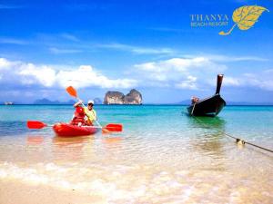 two people in kayaks on the beach with a boat at Thanya Beach Resort - SHA Plus in Ko Ngai