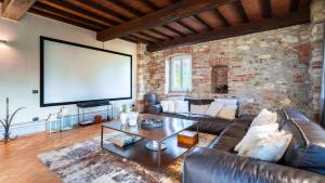 a living room with a leather couch and a large screen at CASCINA MOGLIA 8&1, Emma Villas in Carpeneto