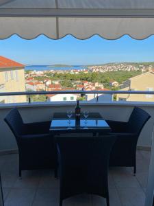 a table with two glasses of wine on a balcony at Apartment Bumbar Sunset in Rogoznica