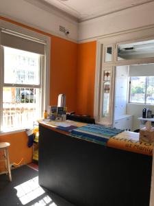 an office with orange walls and a desk with a computer at Manly Bunkhouse in Sydney