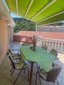 una mesa y sillas en un patio con una sombrilla verde en Beautiful Loft, en Petrovac na Moru