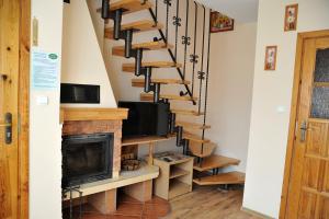 a spiral staircase in a living room with a fireplace at Kapio - domki, pokoje, apartament in Bóbrka