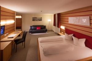 a hotel room with a bed and a desk at Hotel Kanisfluh in Mellau