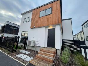 a house with a black door and wooden stairs at CBD Luxury Parkside Living 2 Bedroom With Parking in Christchurch