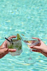 a person holding a drink in front of a pool at Puro Dão Hotel & Spa in Nelas