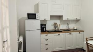 a kitchen with white cabinets and a white refrigerator at Sa Domo de Lillo e Arturo in Bonarcado