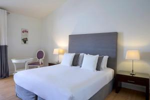 a bedroom with a large white bed and a table at Princess Resort, Santikos Collection in Agia Paraskevi