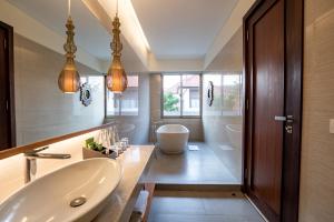 a bathroom with a sink and a bath tub at MERUSAKA Nusa Dua in Nusa Dua