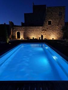 a blue swimming pool in front of a building at night at Chateau de Sainte Jalle in Sainte-Jalle